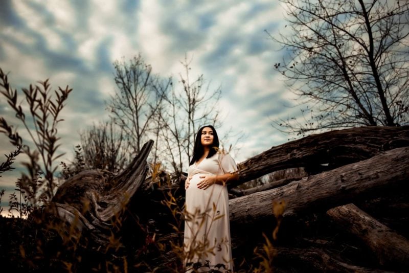 pregnant woman standing between drifted wood