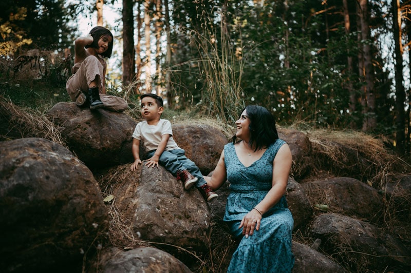 mother looks on as her kids climb rocks in Portland oregon