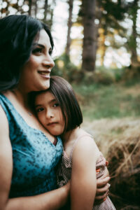 mother and daughter hugging in forest in lake oswego