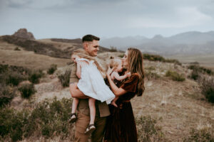 mom dad and two daughters embracing in a field