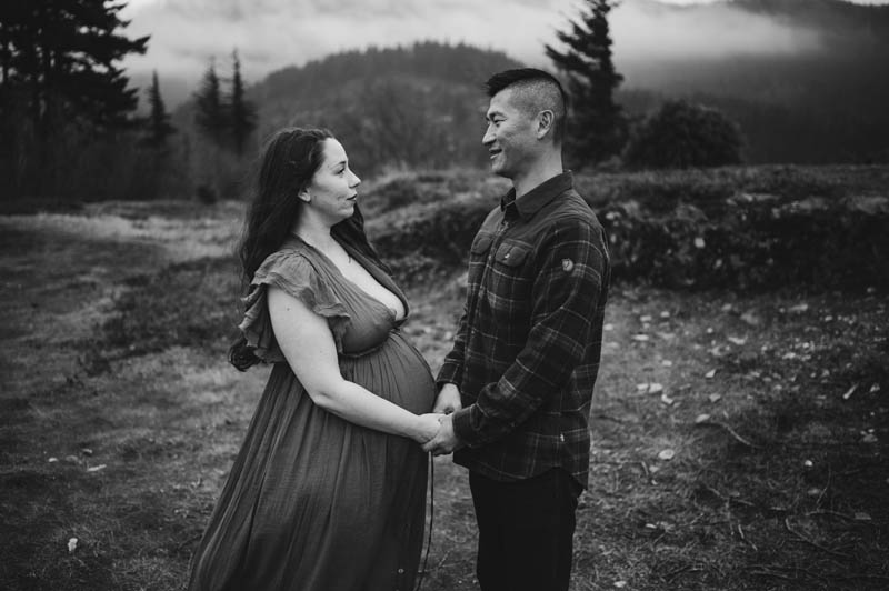 pregnant woman and husband holding hands in the columbia river gorge