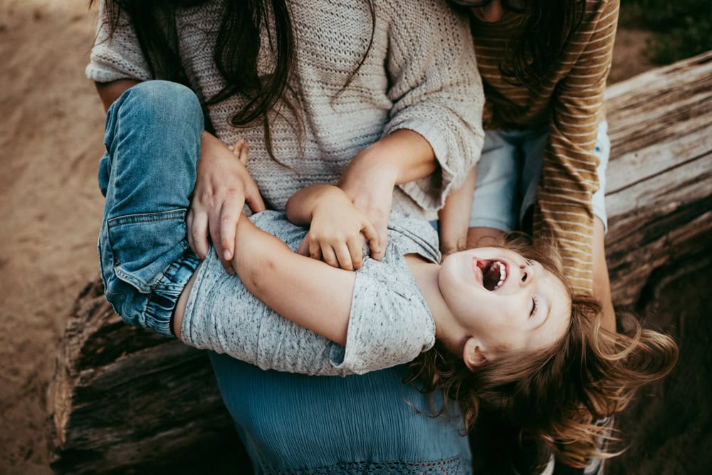 boy laughing while mom tickles him