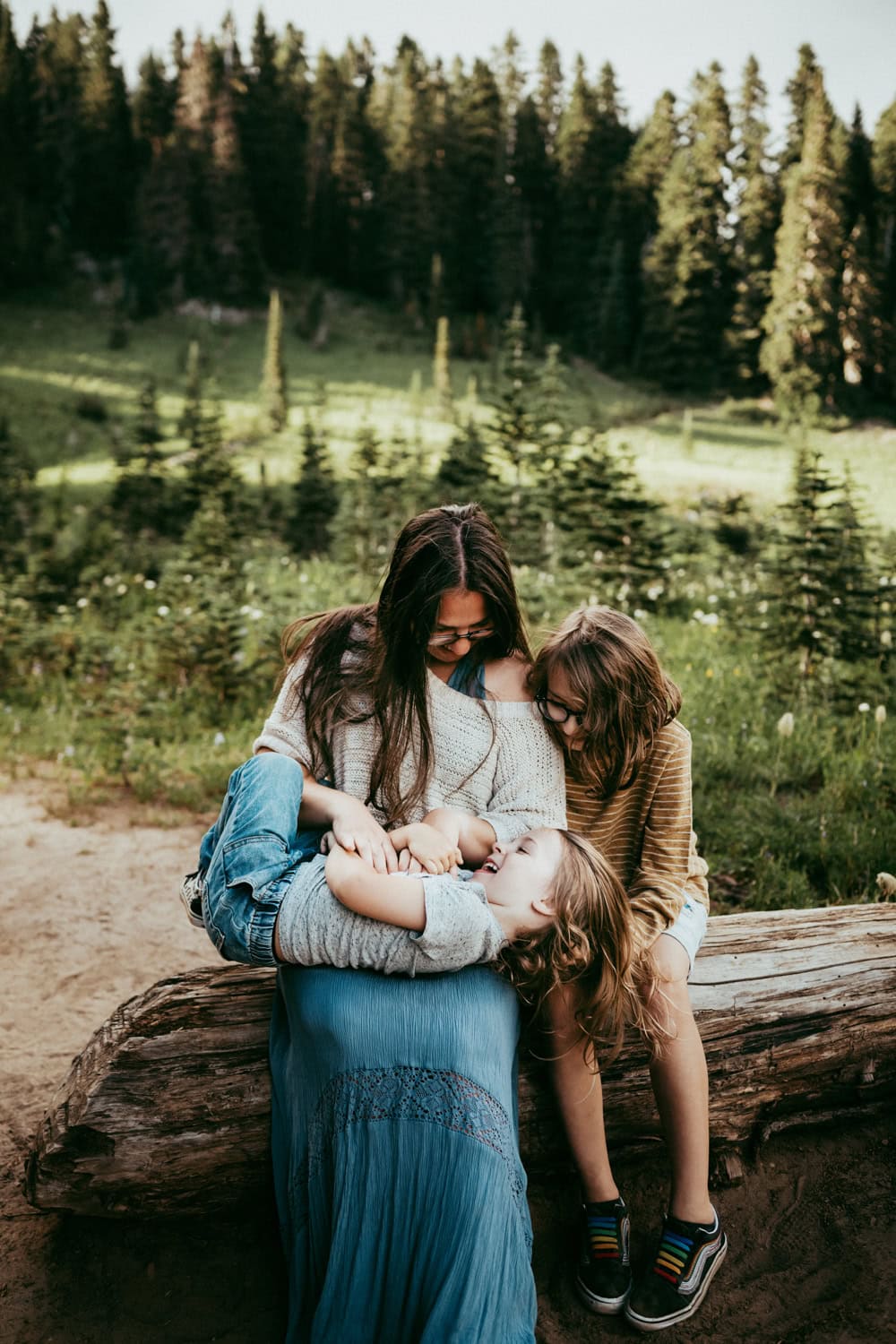 mother and her two kids sitting on a log, playing at Mt Rainier