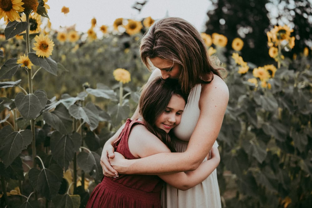 mother and daughter embrace wearing dresses, a beautiful example of what to wear for family photos