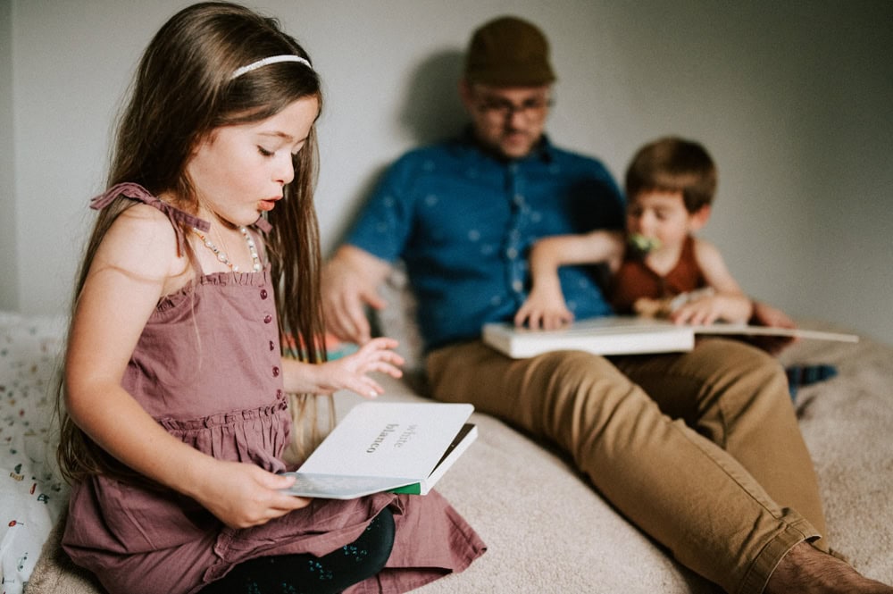 kids reading a book at home with dad